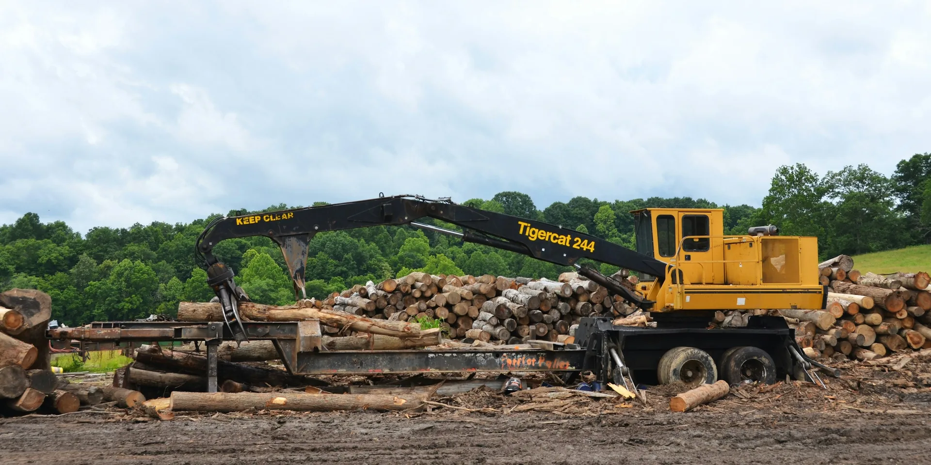 Timber handling equipment alongside stacks of logs at a forest landing